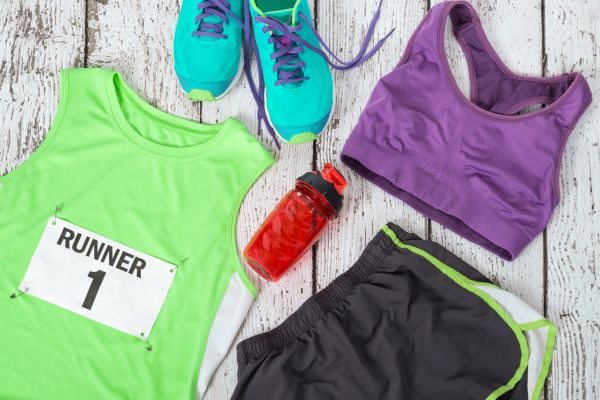 Flat lay of tropical running gear including running shoes, water bottle, and appropriate outfit.
