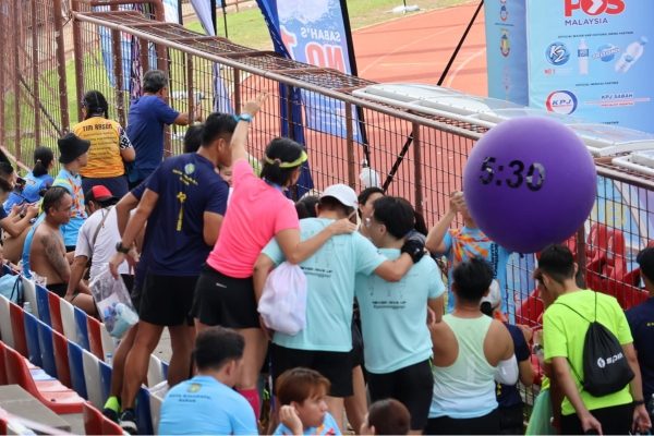 Runner finishing the race happily, greeted by friends and family.
