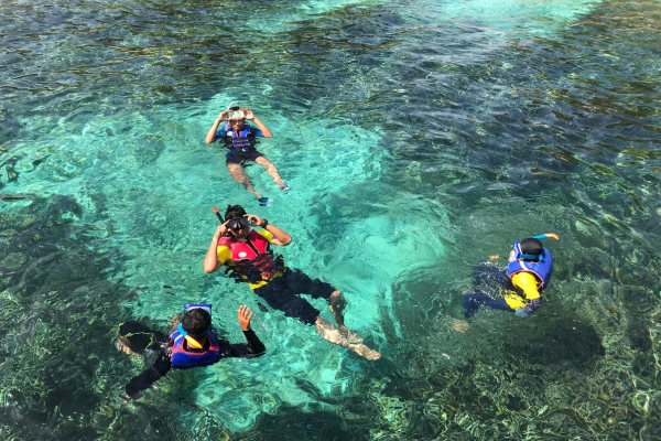 Snorkelers in clear tropical waters with coral reef visible near Sabah islands
