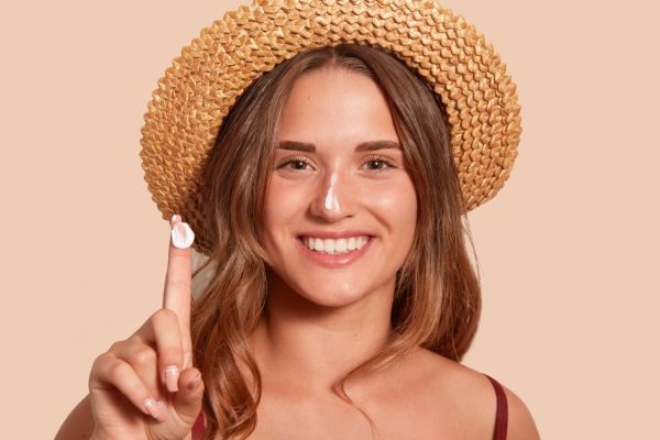 Smiling woman applying sunscreen for sun protection.

